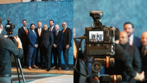 Behind-the-scenes view of Christie’s Photographic Solutions team capturing professional group shots at a corporate event with lighting, backdrop, and client engagement.