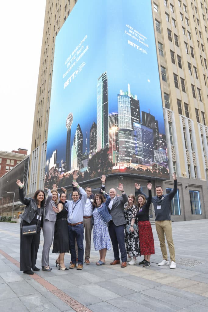 Group of professionals posing in front of a billboard in downtown Dallas, captured by Christie’s Photographic Solutions.