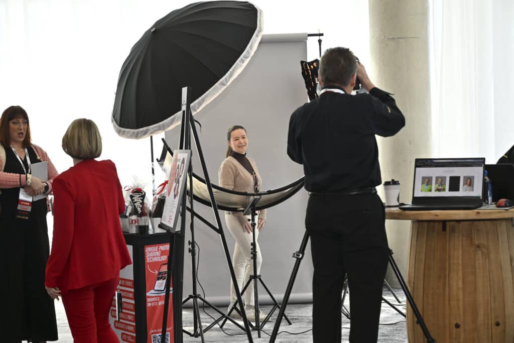 Conference attendee smiling during a luxury on-site headshot session with full studio lighting, captured by Christie’s Photographic Solutions.