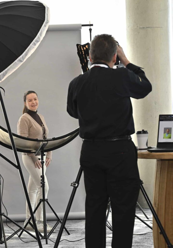 Conference attendee smiling during a luxury on-site headshot session with full studio lighting, captured by Christie’s Photographic Solutions.