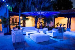 Stylish white lounge seating beneath blue uplighting at an outdoor corporate event, captured by Christie’s Photographic Solutions.