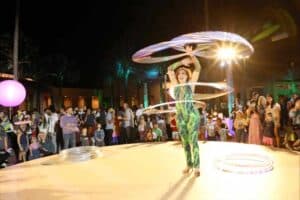 Professional hula hoop artist performing at a lively corporate event with an engaged evening crowd, captured by Christie’s Photographic Solutions.