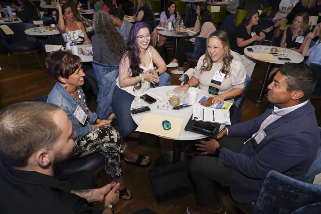 Corporate event attendees engaged in a lively roundtable discussion during a networking session, captured by Christie’s Photographic Solutions.