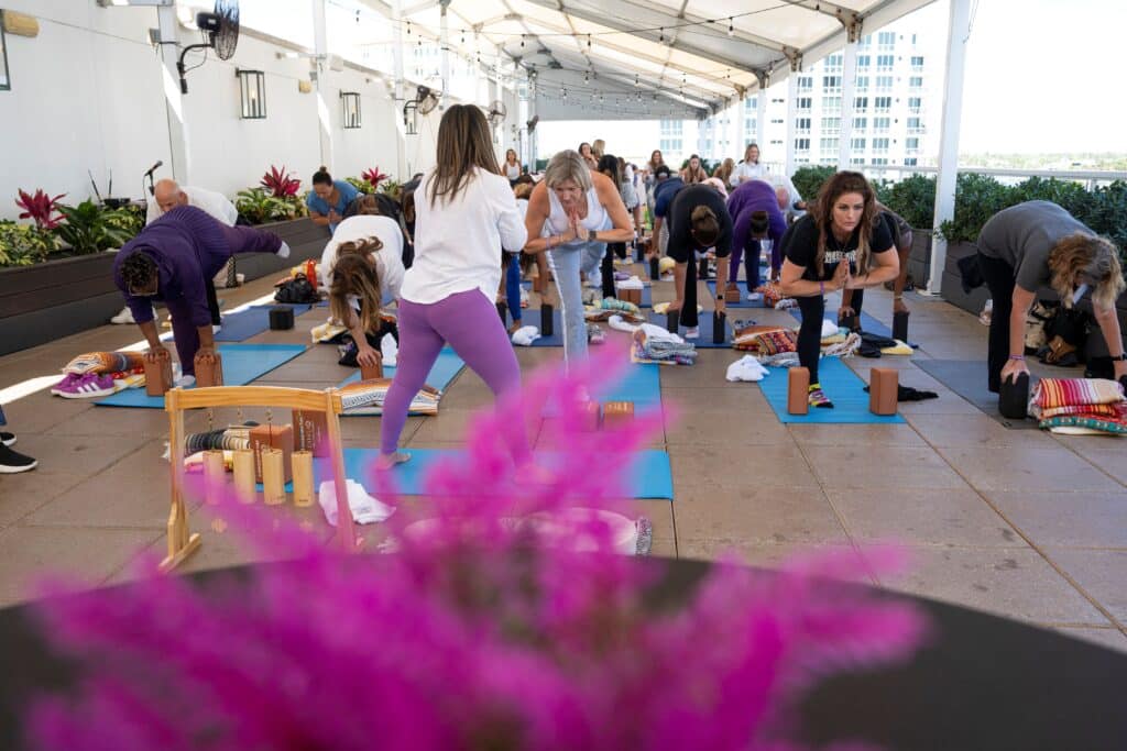 Attendees participating in a guided yoga session during a corporate wellness event, captured by Christie’s Photographic Solutions.