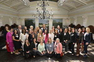 Professional attendee group portrait inside an elegant historic venue beneath a grand chandelier, captured by Christie’s Photographic Solutions.