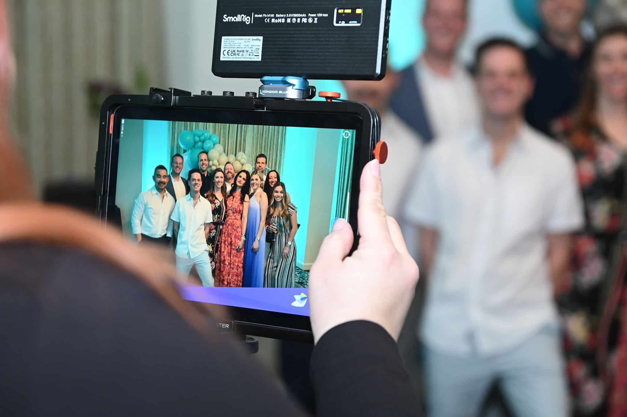 Guests posing for a group photo using the iLite Roaming Photo Booth at a corporate event, captured by Christie’s Photographic Solutions.